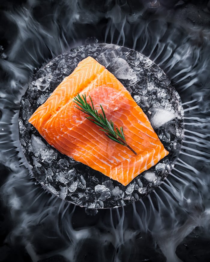 High-quality raw salmon fillet on ice with a sprig of rosemary, perfect for gourmet dishes.