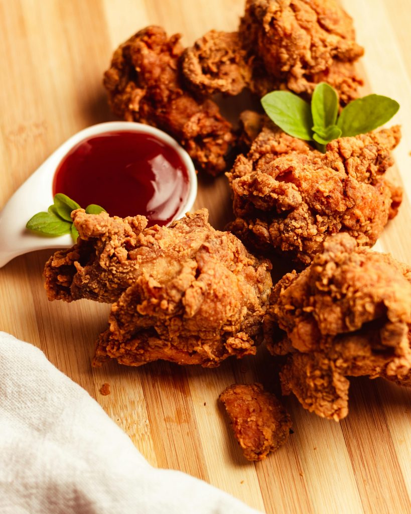 pexels-photo-17282046-17282046 Delicious crispy fried chicken served with a tangy dipping sauce on a wooden board.
